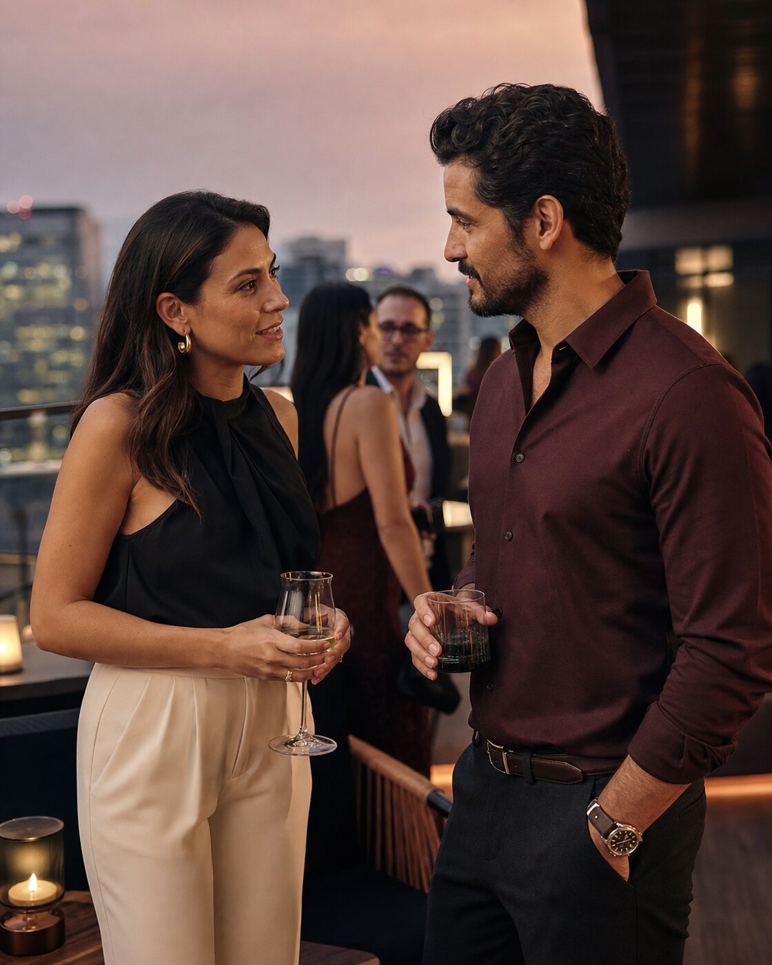 Two adults talk with interest at a social gathering at dusk